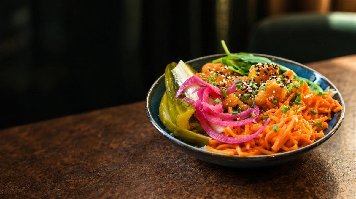 Le Poulet de Satiō, poulet frit laqué à la coréenne, carottes au sésame et pickles, dans un bol sur une table en pierre